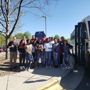 Group of high school students standing next to a bus