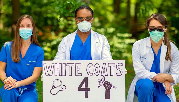 Photo of radiology group holding up sign that says "White Coats for Justice"