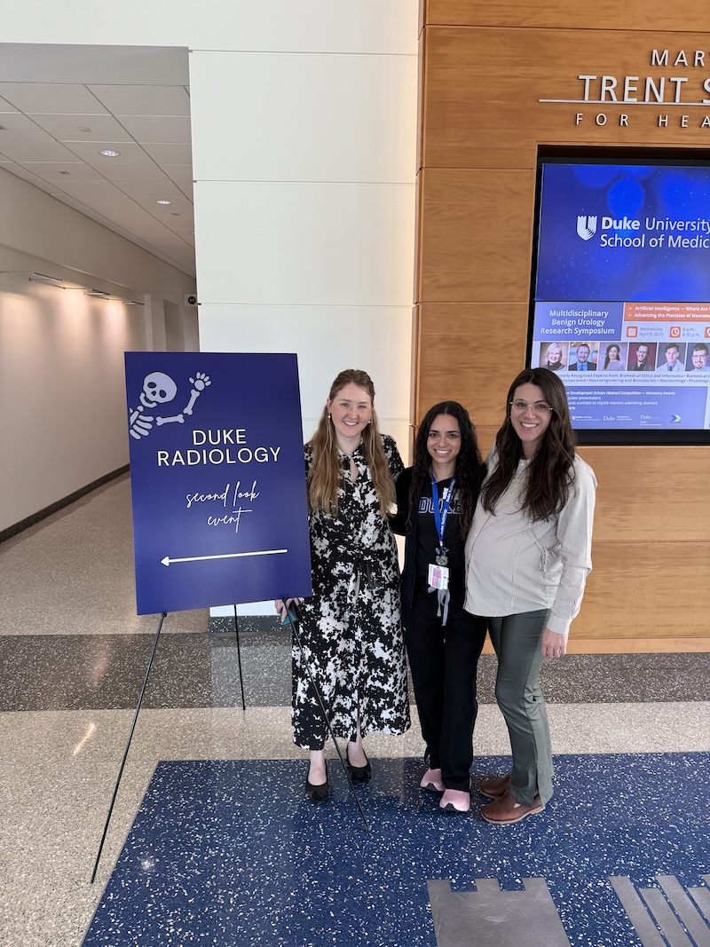 People next to a Duke Radiology poster