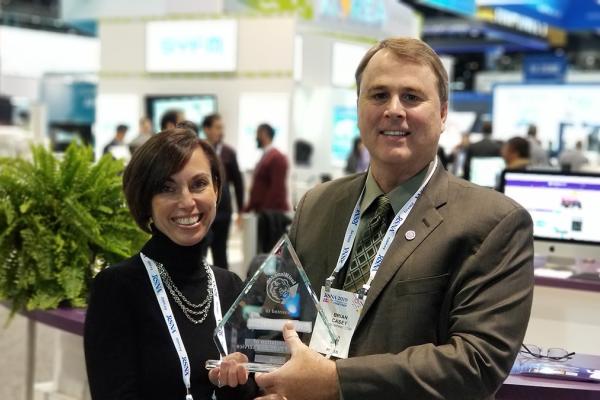 Photo of two people holding an award